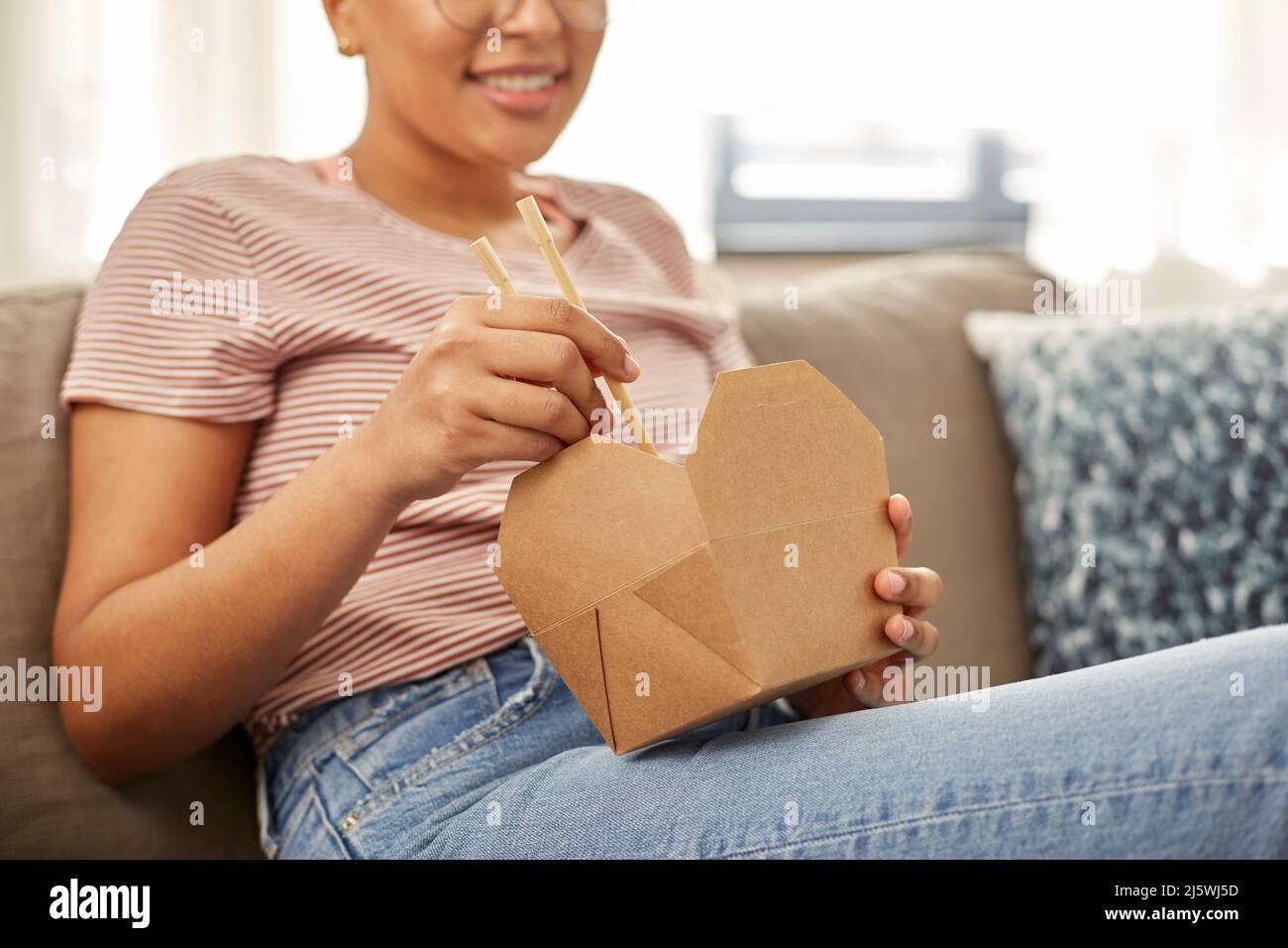 african woman eating food with chopsticks at home Stock Photo