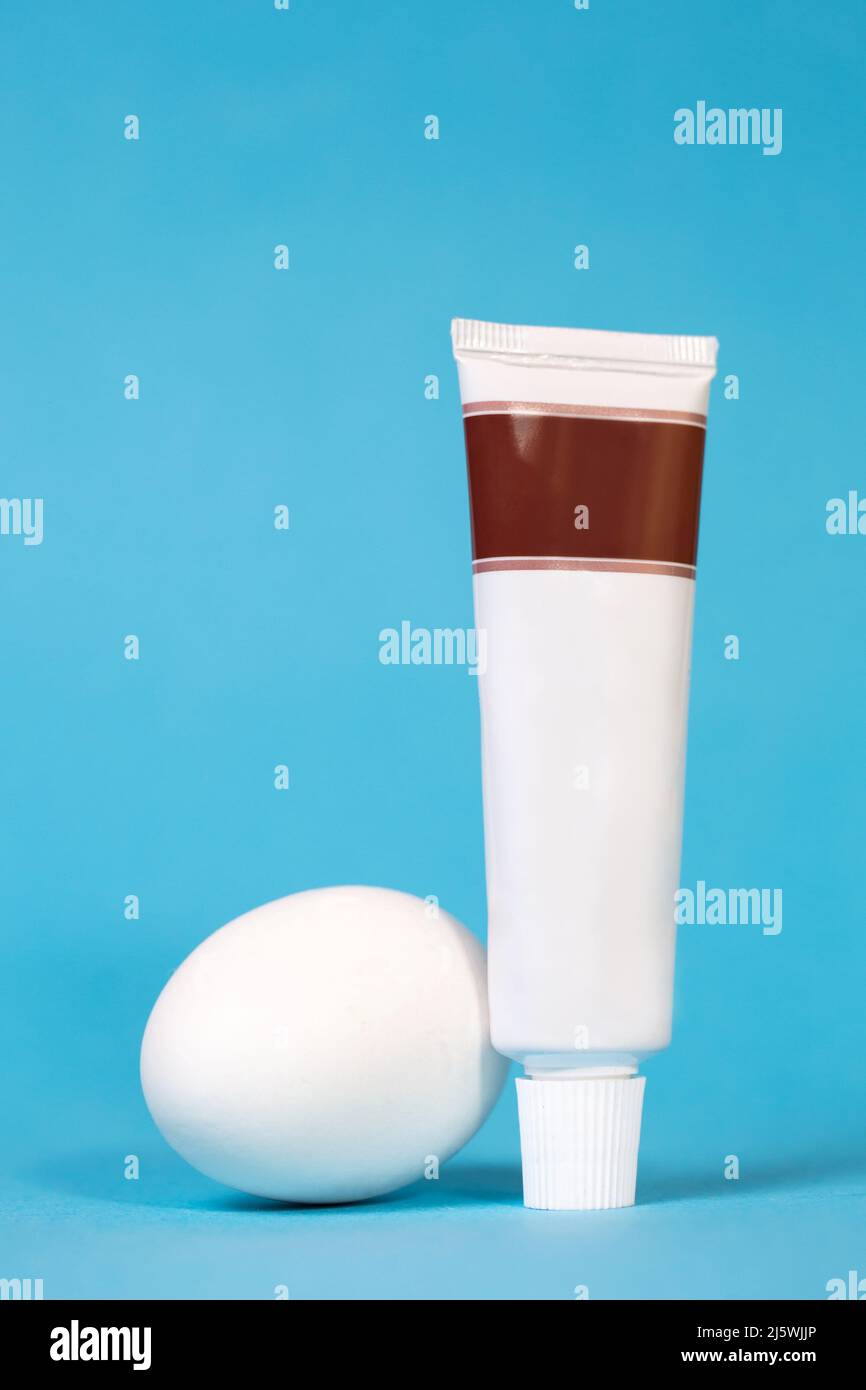 an egg and a tube of toothpaste without a logo on a blue background