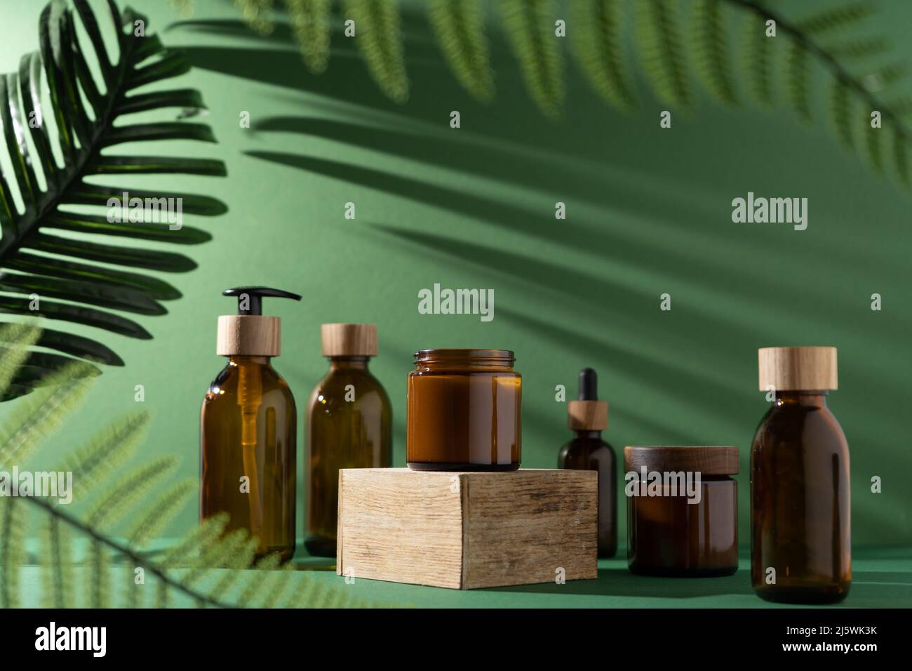 Bottles for cosmetics and cream on a pedestal, green background with ...