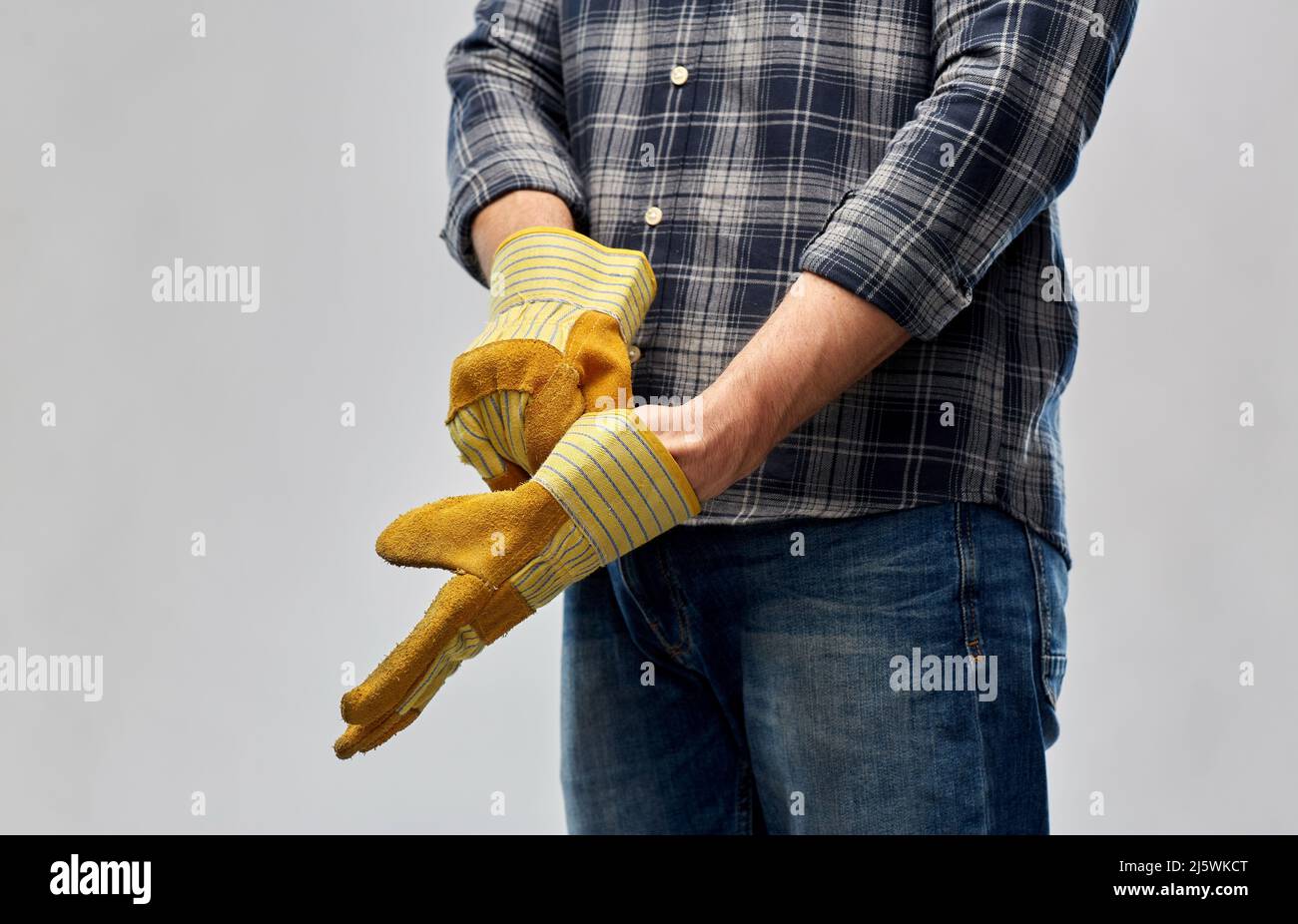 man or builder putting protective gloves on Stock Photo