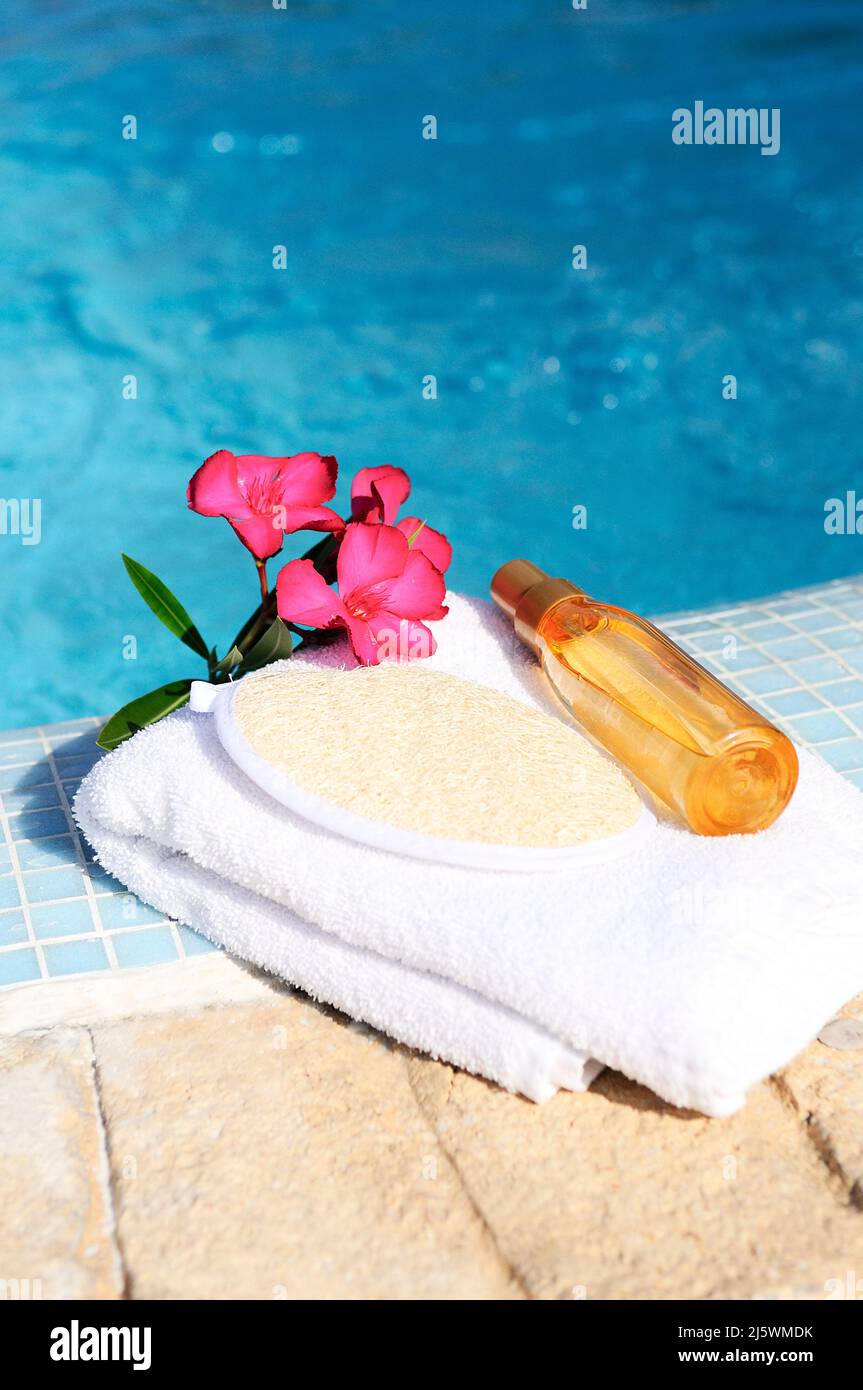 massage oil, shellfish and white towel beside a pool Stock Photo