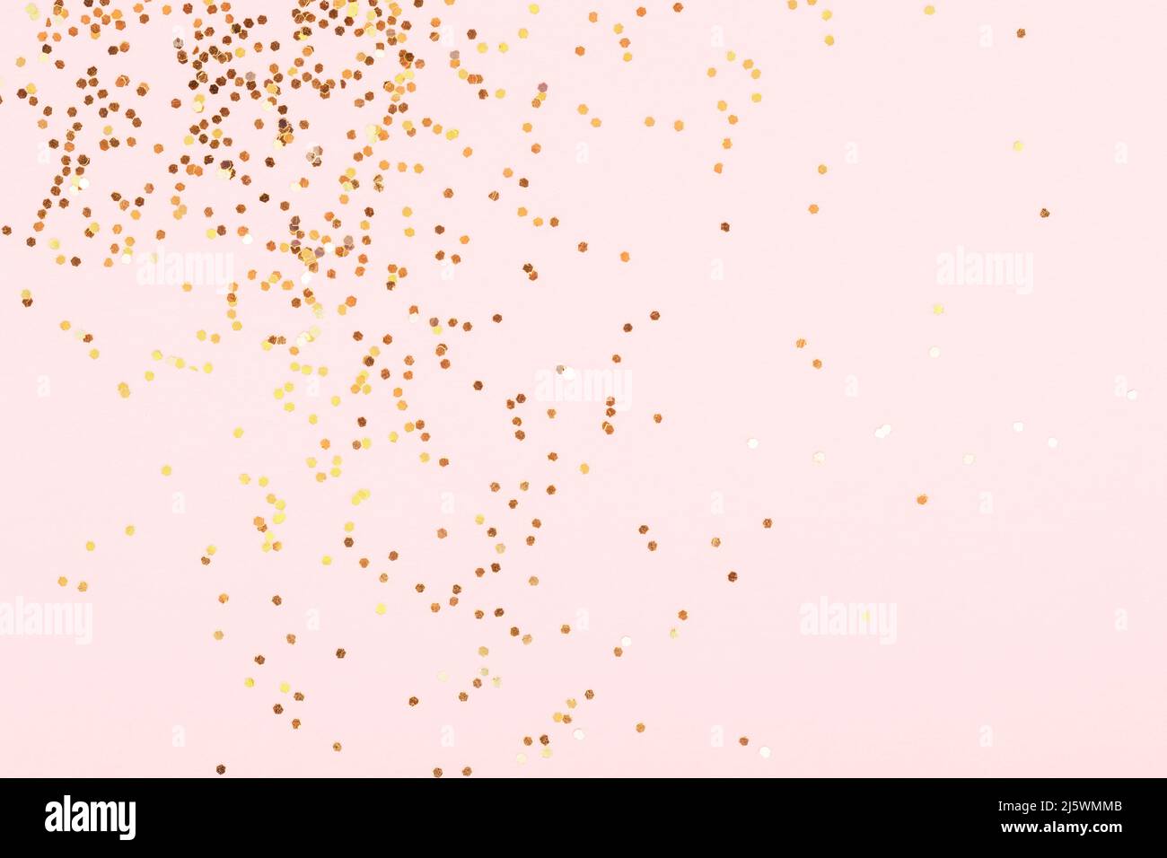 Scattering of golden confetti on pink background. Stock Photo