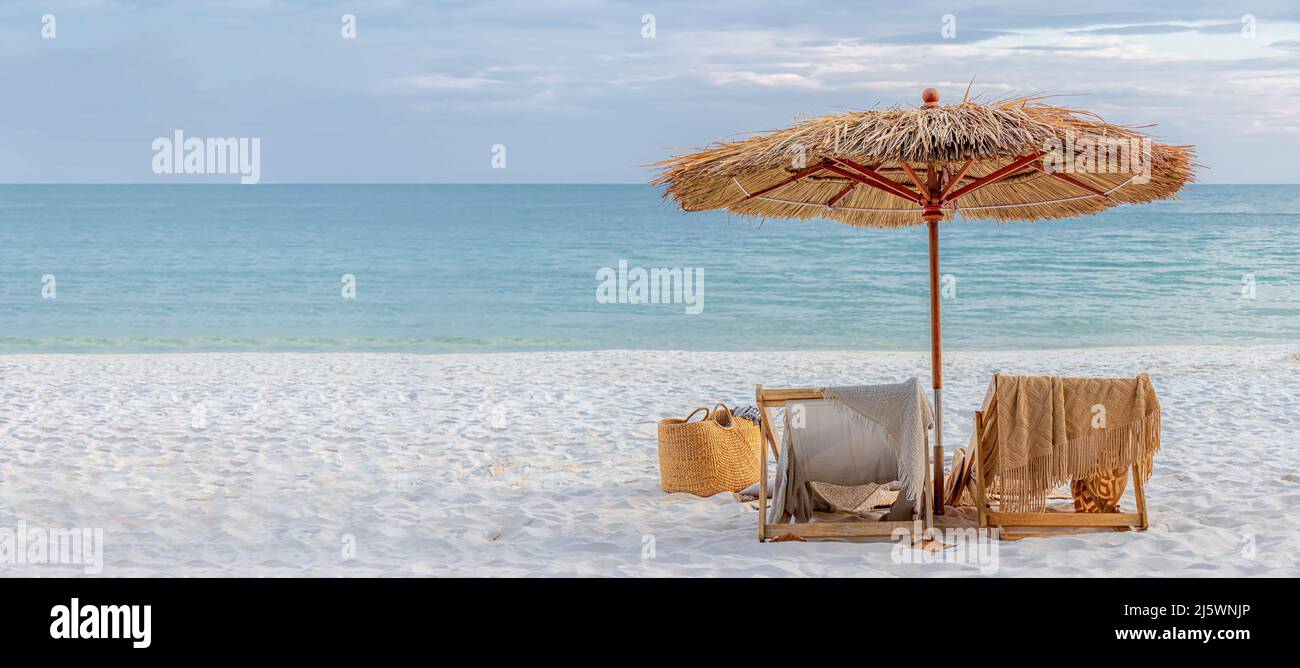 beautiful tranquil white sand beach with two beach chair and thatched umbrella with copy space. romantic summer vacation at tropical private island Stock Photo