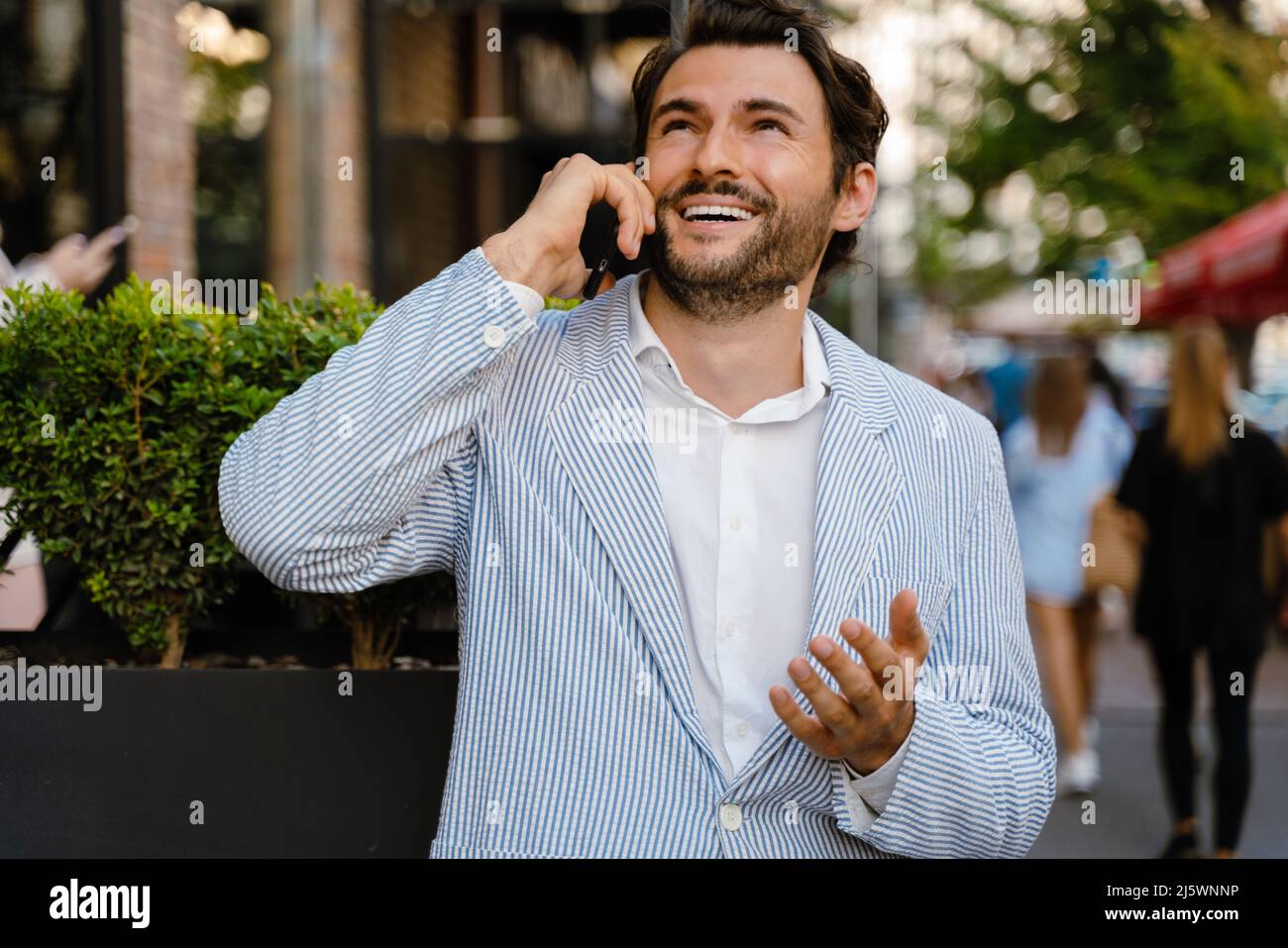 Young man gesturing and talking on mobile phone while standing outdoors Stock Photo