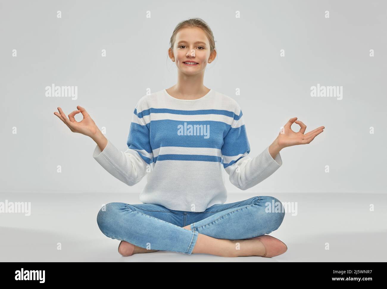 smiling teenage girl meditating in lotus pose Stock Photo