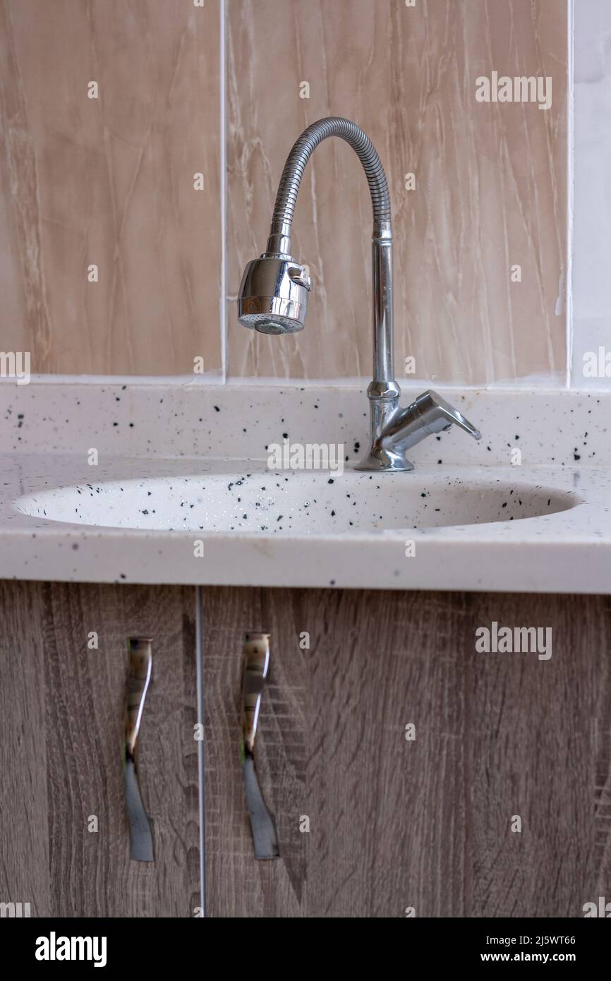 Flexible faucet and marble sink in kitchen. doors with fittings