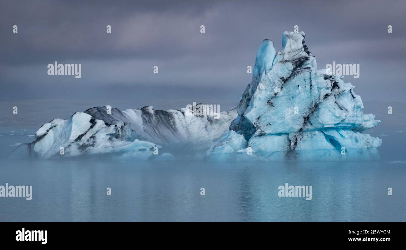 Eisberg in der Gletscherlagune Jökulsárlón, Südwest-Island. Die schwarzen Linien im Eis sind Vulkanasche subglazialer Ausbrüche der Grímsvötn. Stock Photo