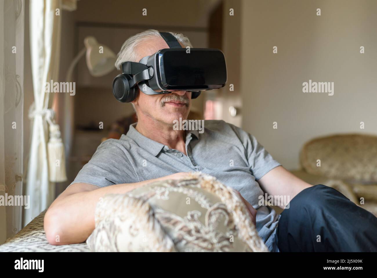 Senior man using VR glasses at home Stock Photo