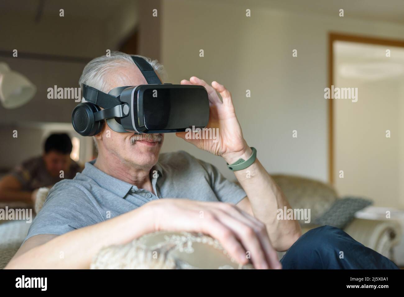Senior man using VR glasses at home Stock Photo