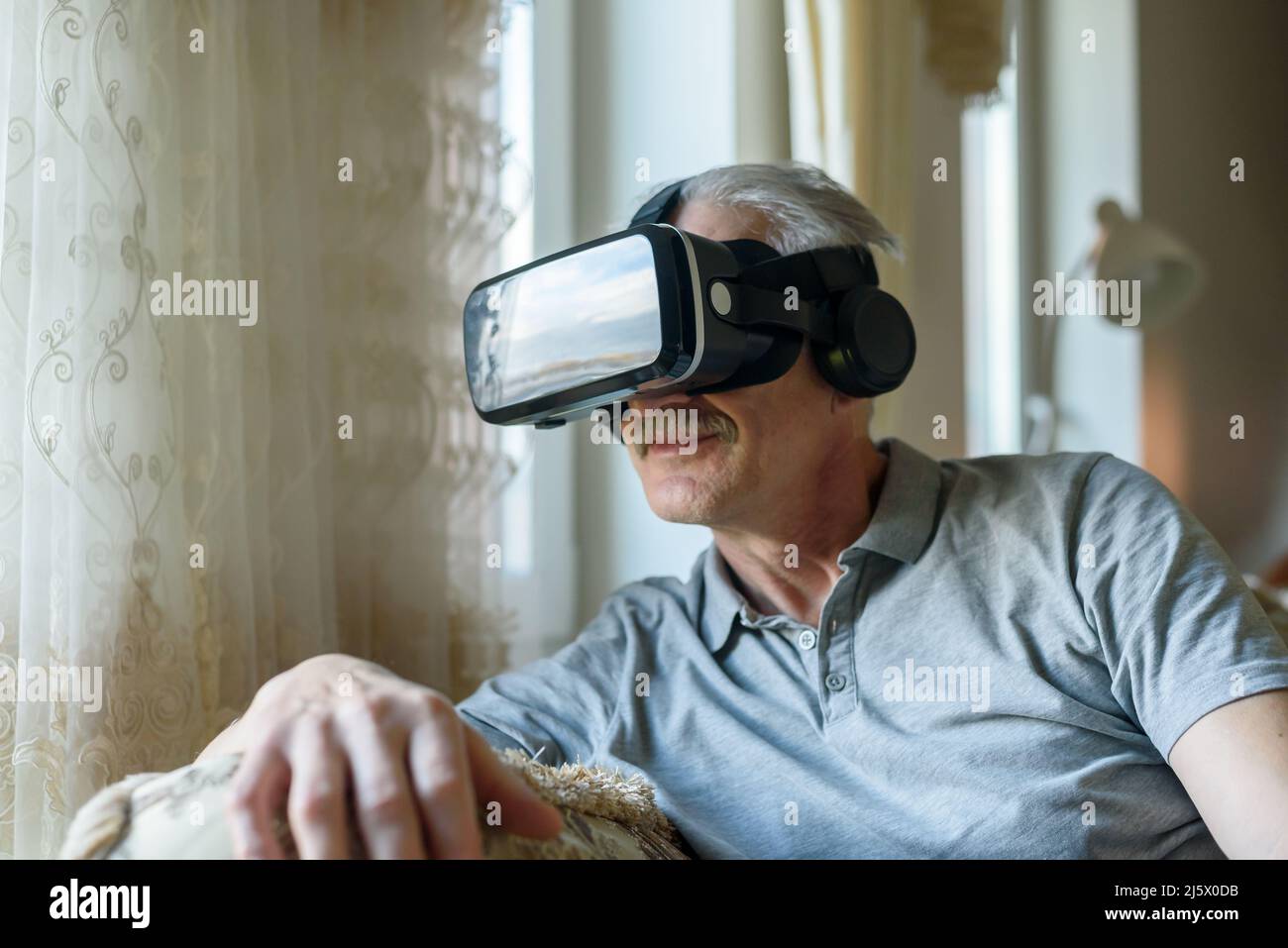 Senior man using VR glasses at home Stock Photo