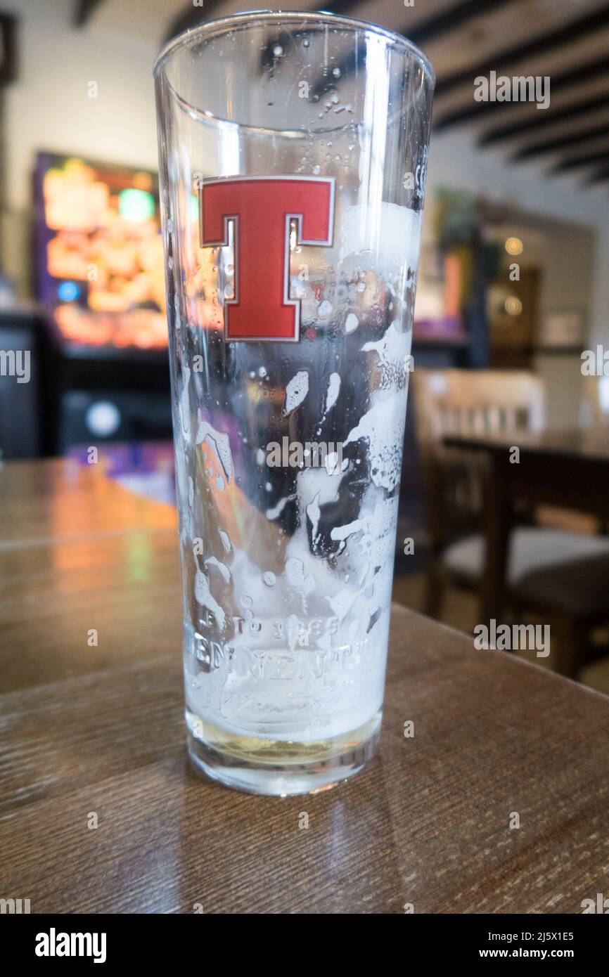 An empty glass of beer resting in an empty pub Stock Photo