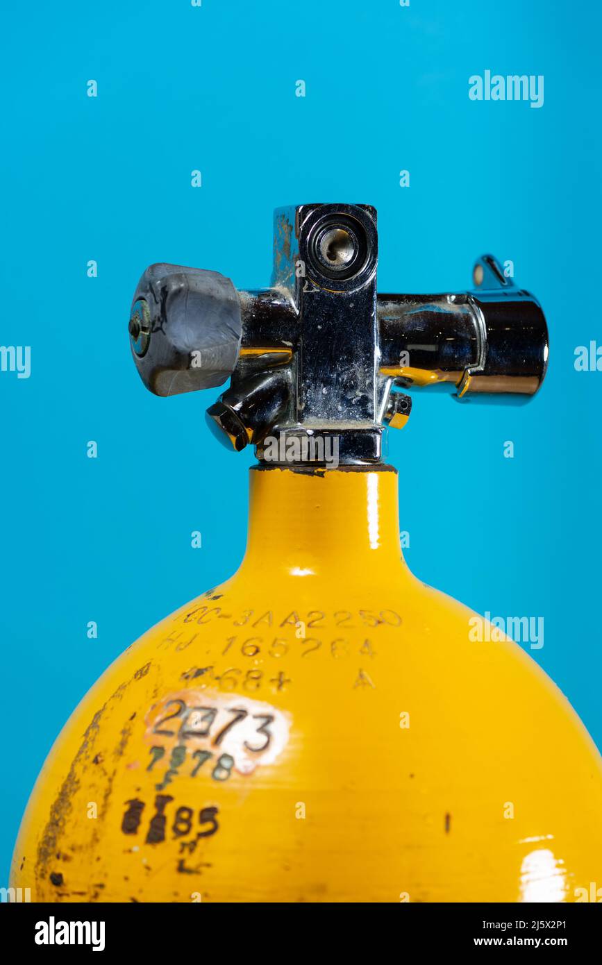 Vintage yellow steel scuba tank with a j valve on a blue background