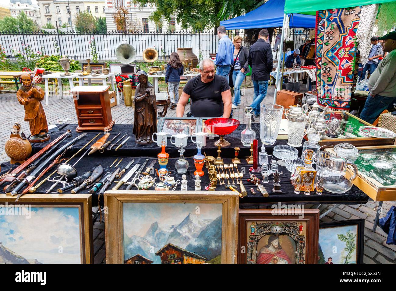 Stallholder and a table with a display of bric-a-brac for sale at a local roadside flea market in Bucharest, capital city of Romania, central Europe Stock Photo