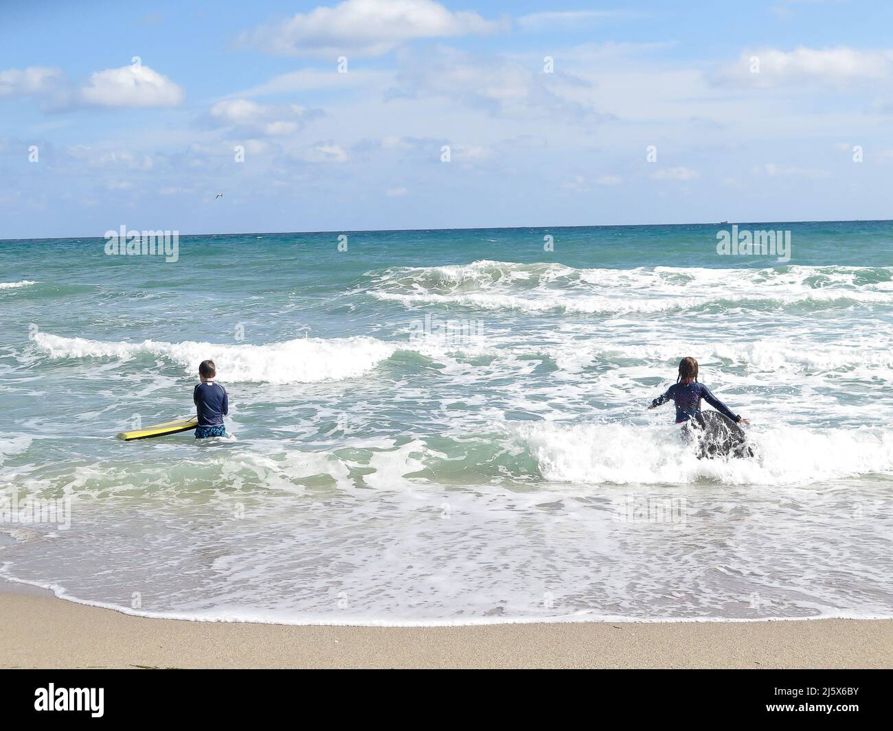 Kids playing in the surf with boogie boards at west Palm Beach, Florida