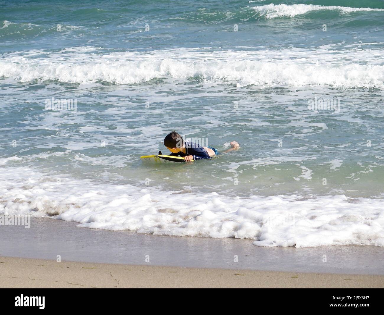 Kids playing in the surf with boogie boards at west Palm Beach, Florida