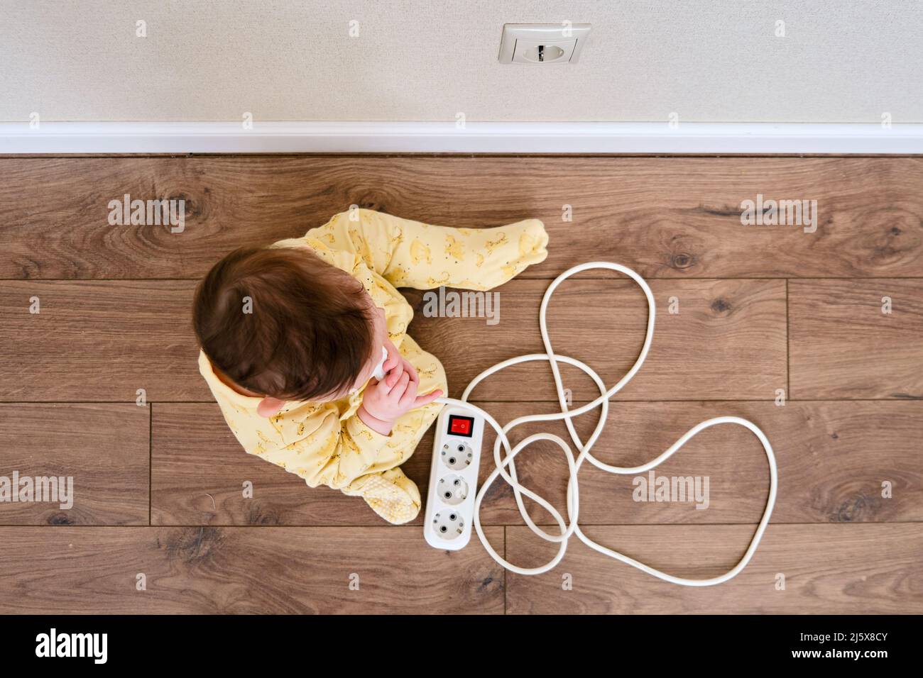Toddler baby boy plays with electric wires while sitting on the floor