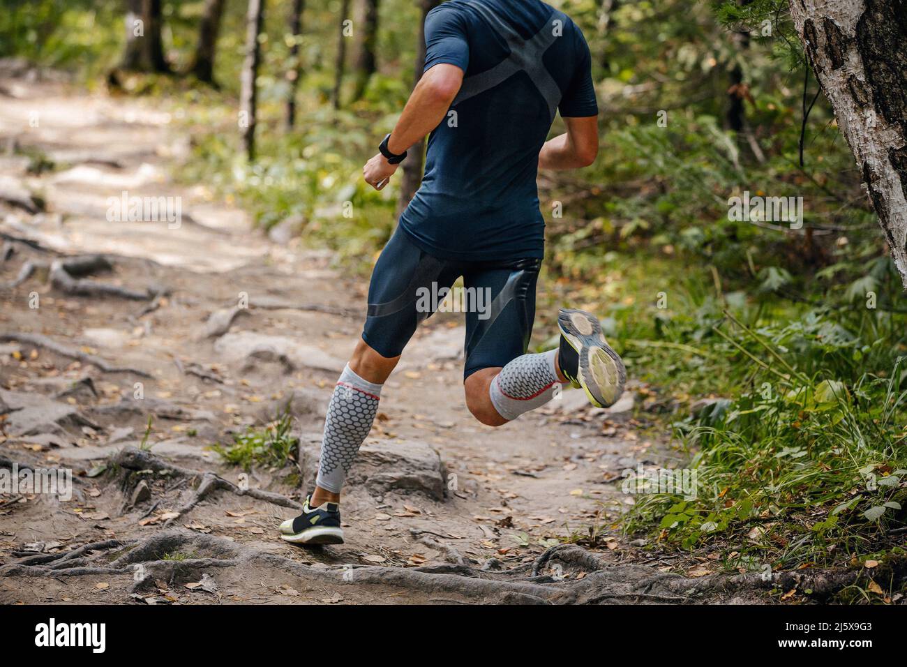 male athlete running in forest in compression calf sleeve Stock Photo
