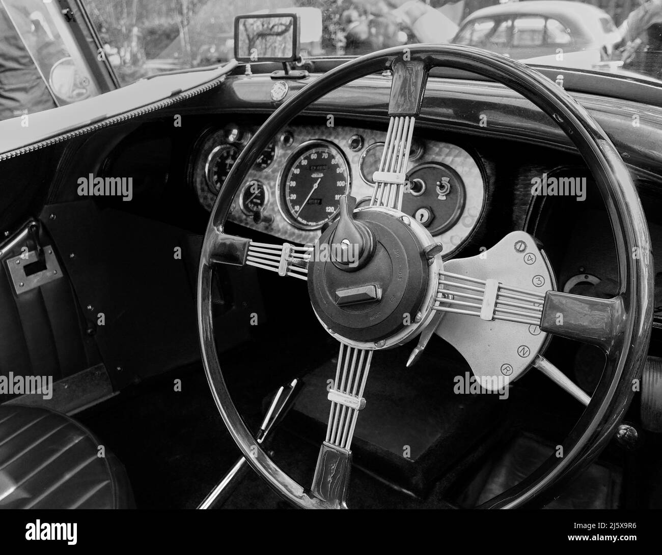 Black and white mage showing the very large steering wheel and dashboard of a pre war car Stock Photo
