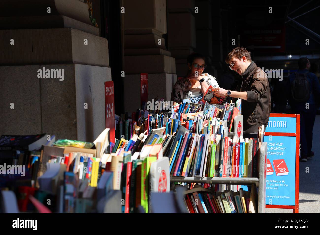 Two people find treasure while looking through used books outside
