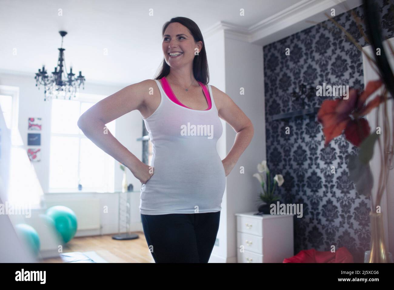 Happy pregnant woman in tank top at home Stock Photo