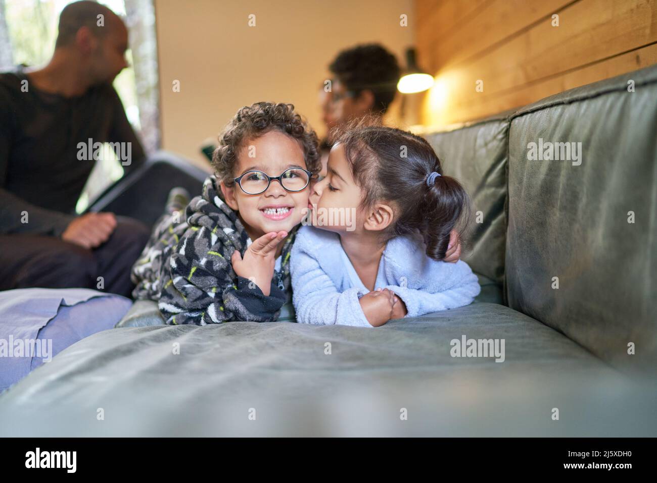 Portrait cute sister kissing brother on living room floor Stock Photo