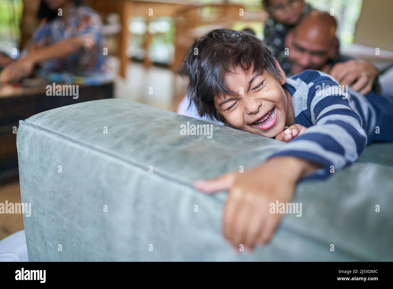 Laughing boy being tickled on sofa Stock Photo