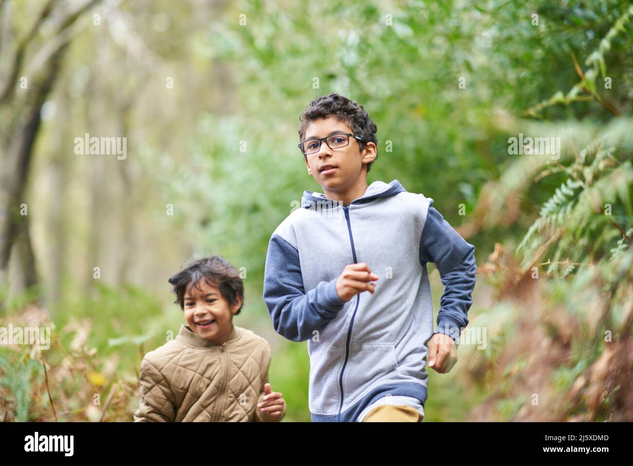 Brothers running together in woods Stock Photo