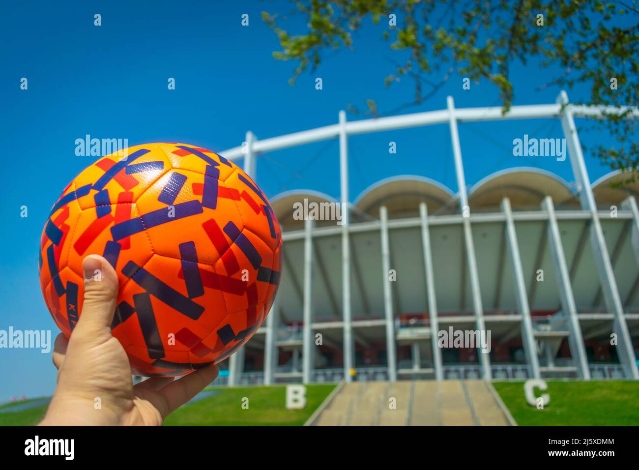 Hand holding Colorful Football with football stadium background Qatar World Cup 2022 Concept close-up Stock Photo