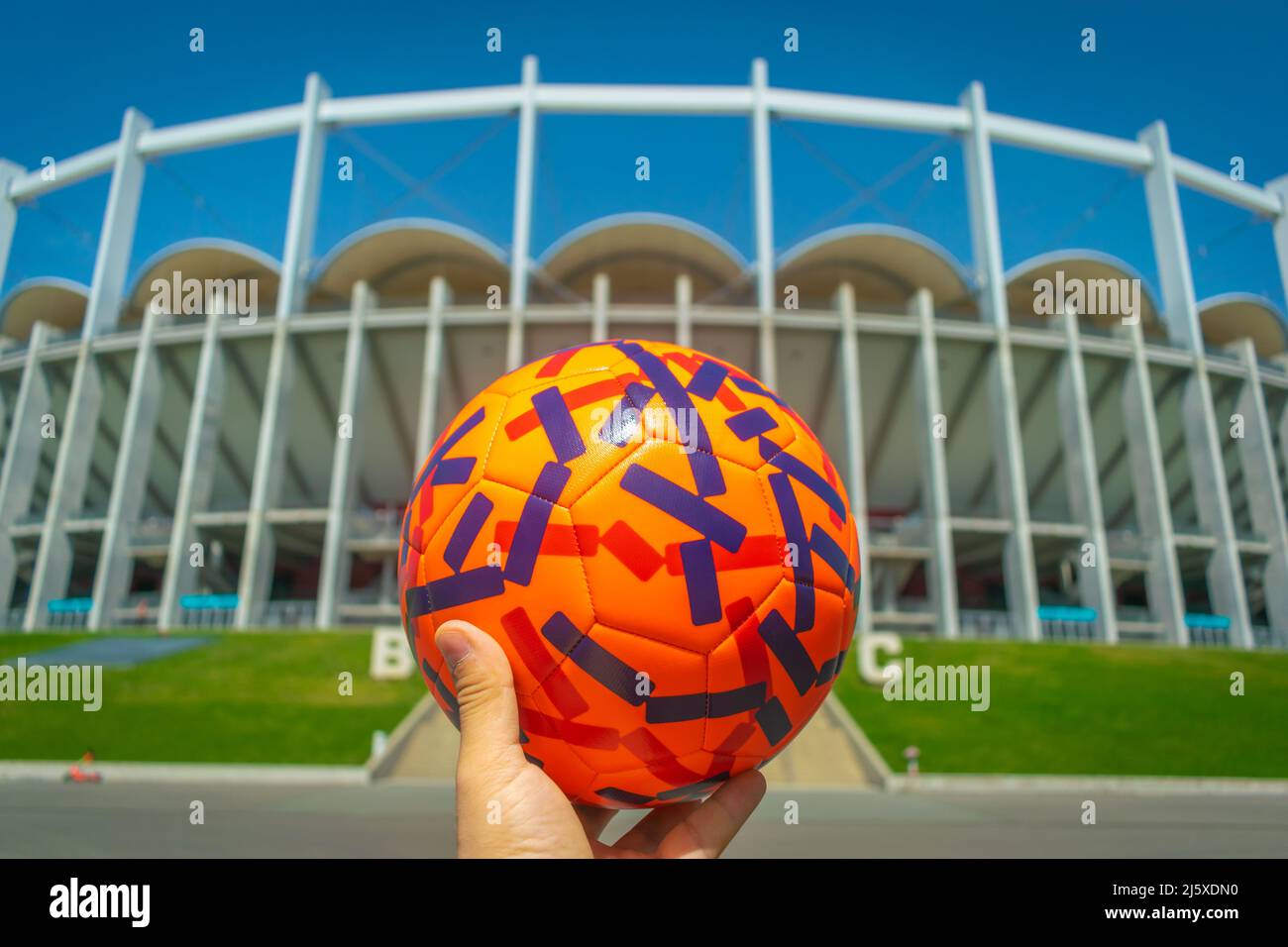 Hand holding Colorful Football with football stadium background Qatar World Cup 2022 Concept close-up Stock Photo