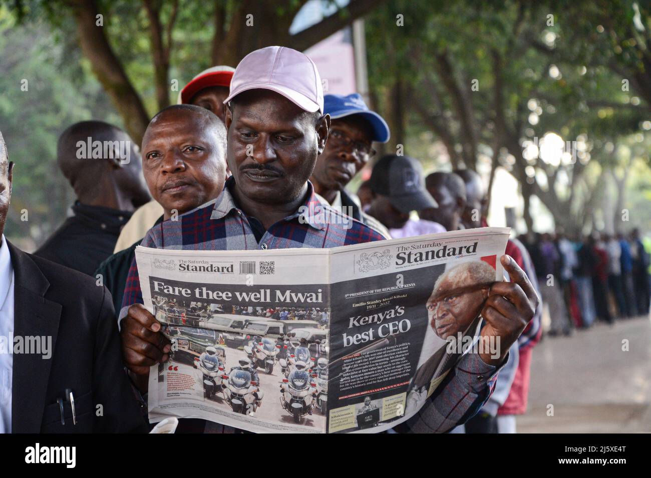 Nairobi, Kenya. 25th Apr, 2022. A member of the public reads a newspaper reporting on the death of the former president of Kenya Mwai Kibaki as he queues to see his body which is lying in state for the second day at the Parliament Building. The former head of state, who ruled for eight years (December 2002 until April 2013) died on April 22, 2022, as announced by the current president Uhuru Kenyatta. Credit: SOPA Images Limited/Alamy Live News Stock Photo