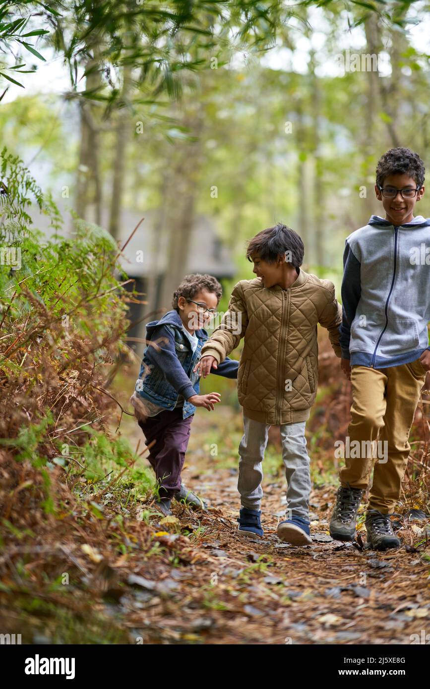 Happy brothers hiking on trail in woods Stock Photo