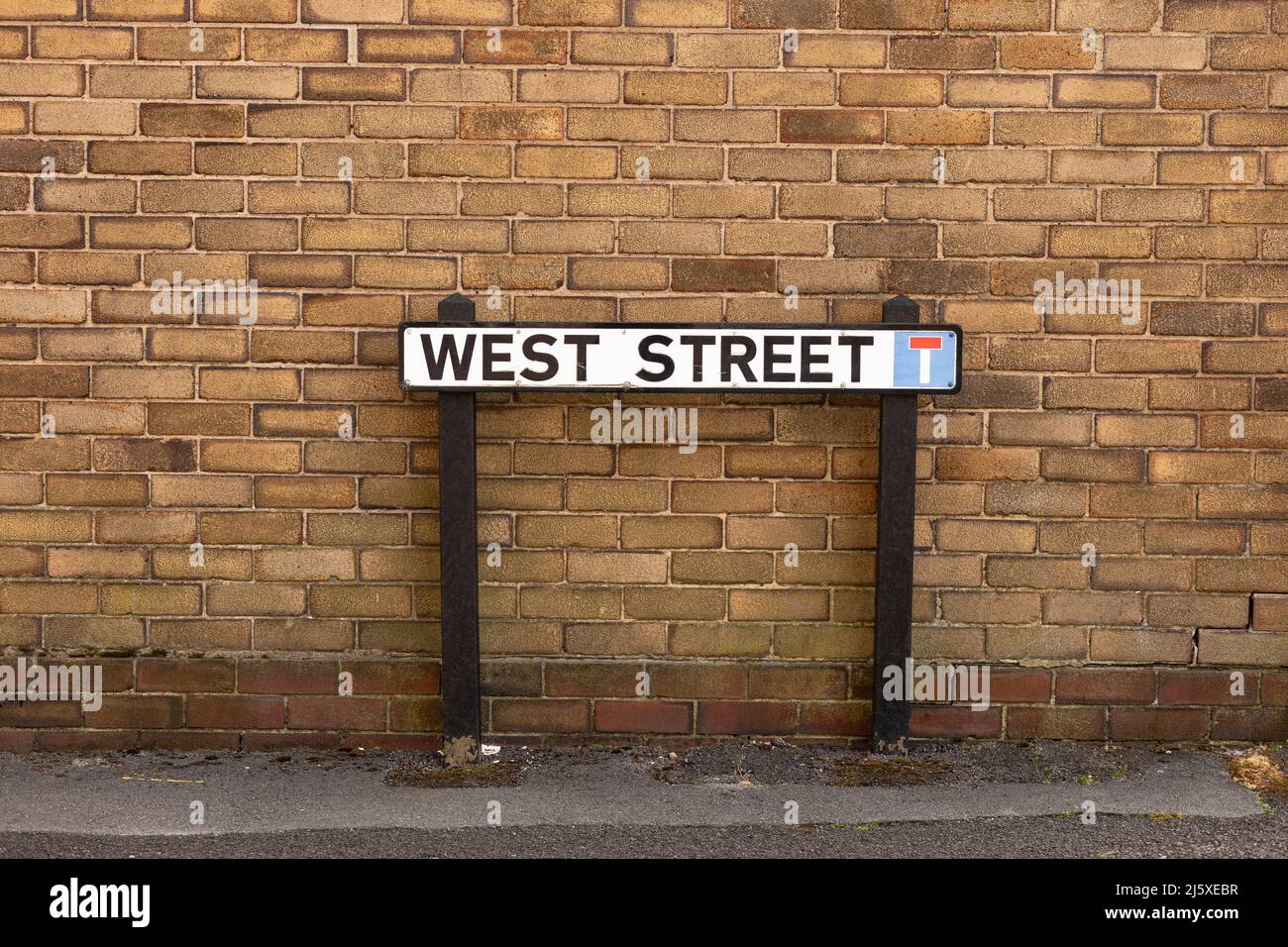 street sign depicting west street and a brick wall background Stock Photo
