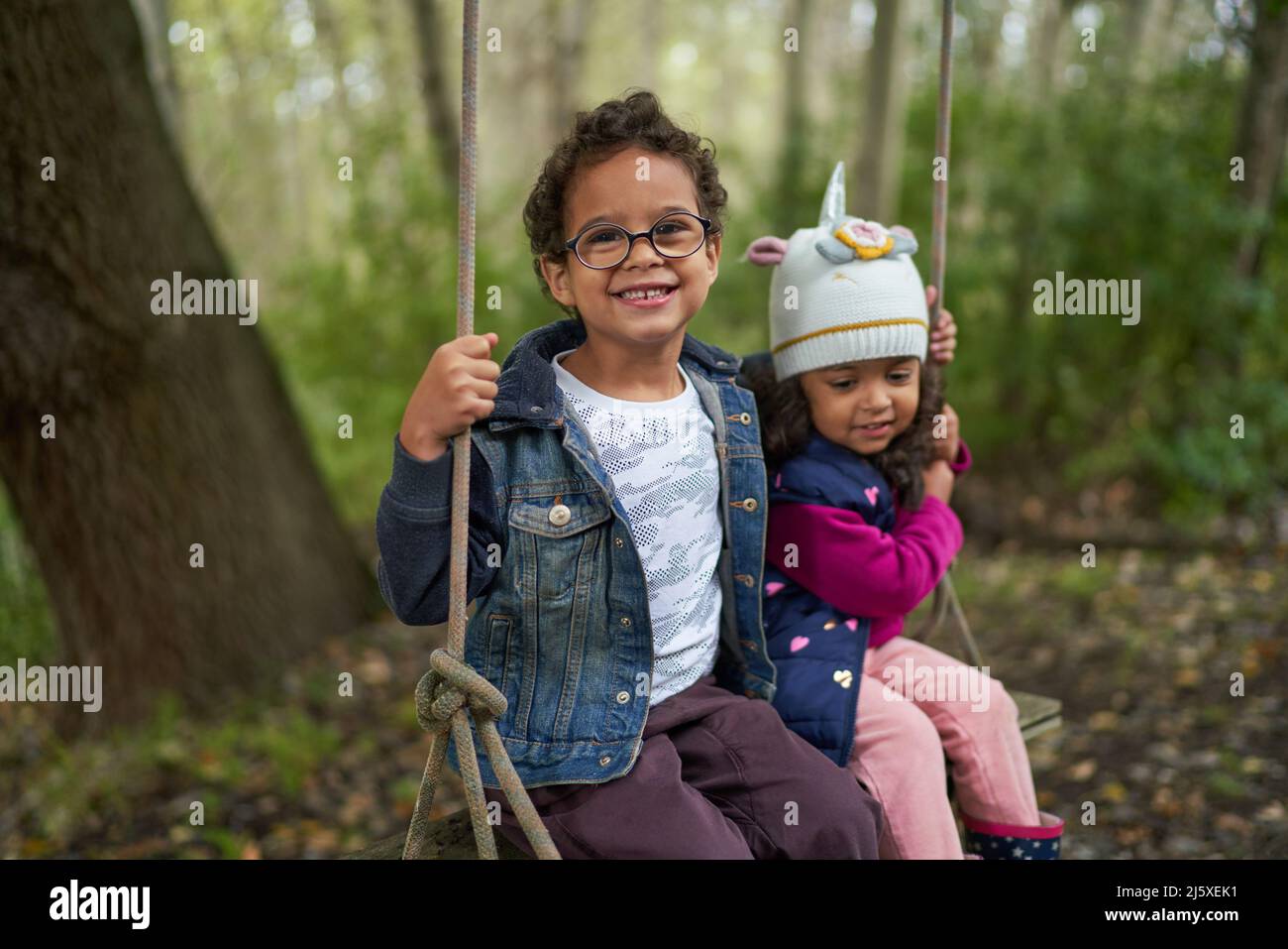 Portrait cute brother and sister on swing in woods Stock Photo - Alamy
