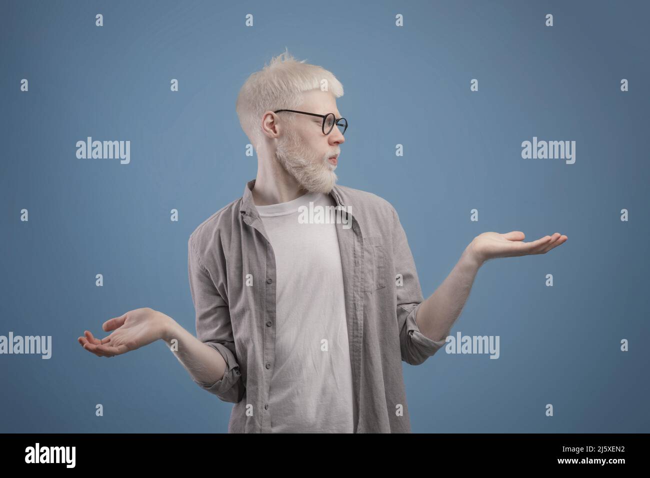 Making choice. Young albino man making scales with his empty hands, doubtful guy comparing options, copy space Stock Photo