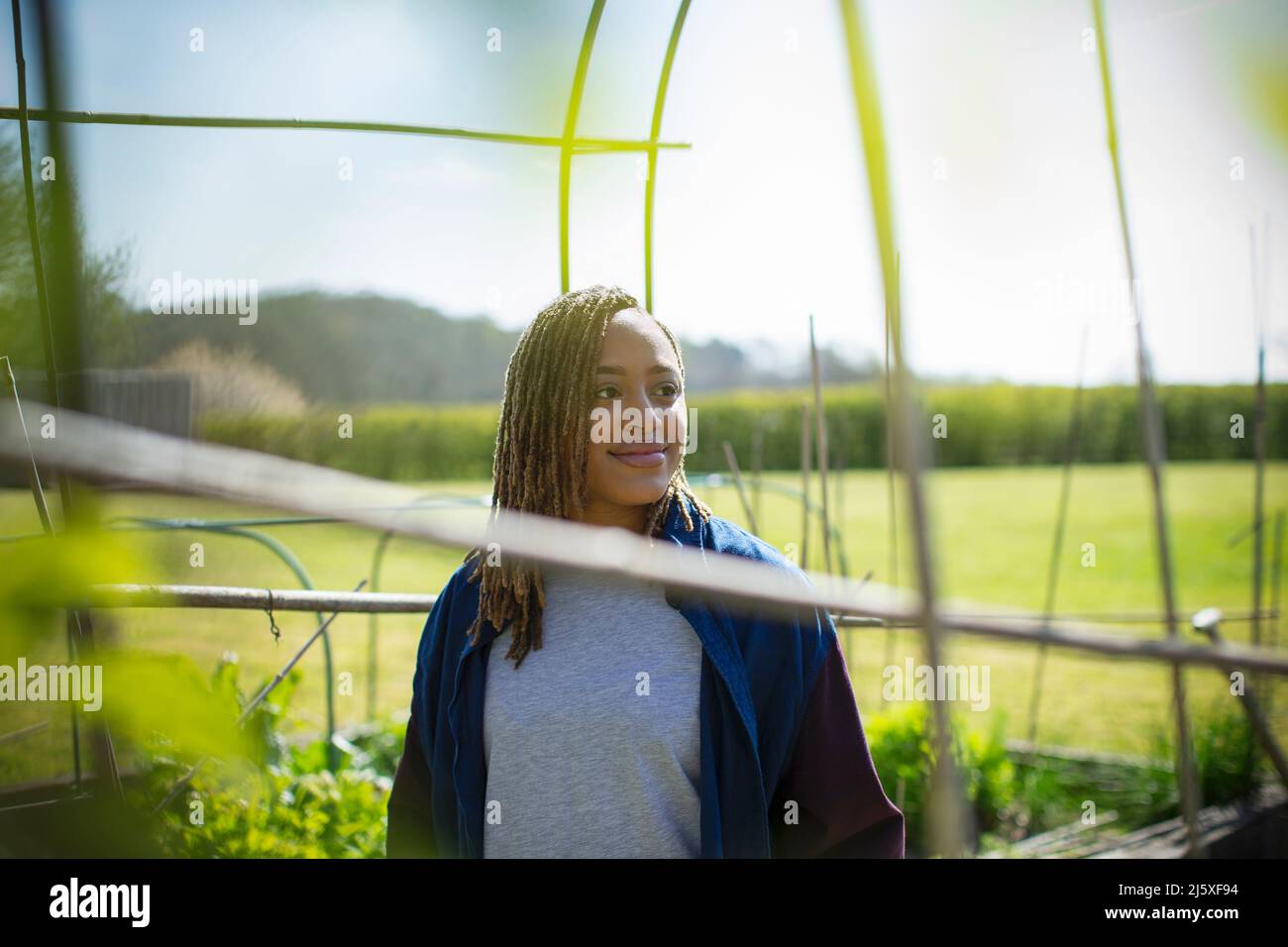 Smiling young woman in sunny garden Stock Photo