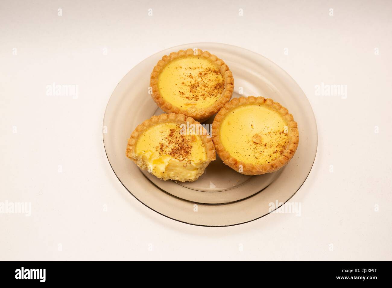 Three home made Egg Custard Tart on glass plate isolated on white Stock Photo