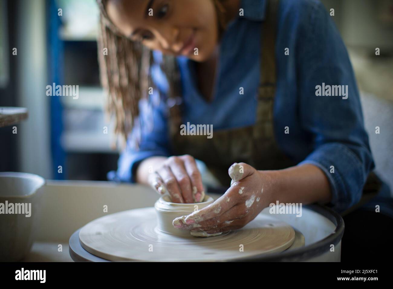 Young woman at pottery wheel in art studio Stock Photo