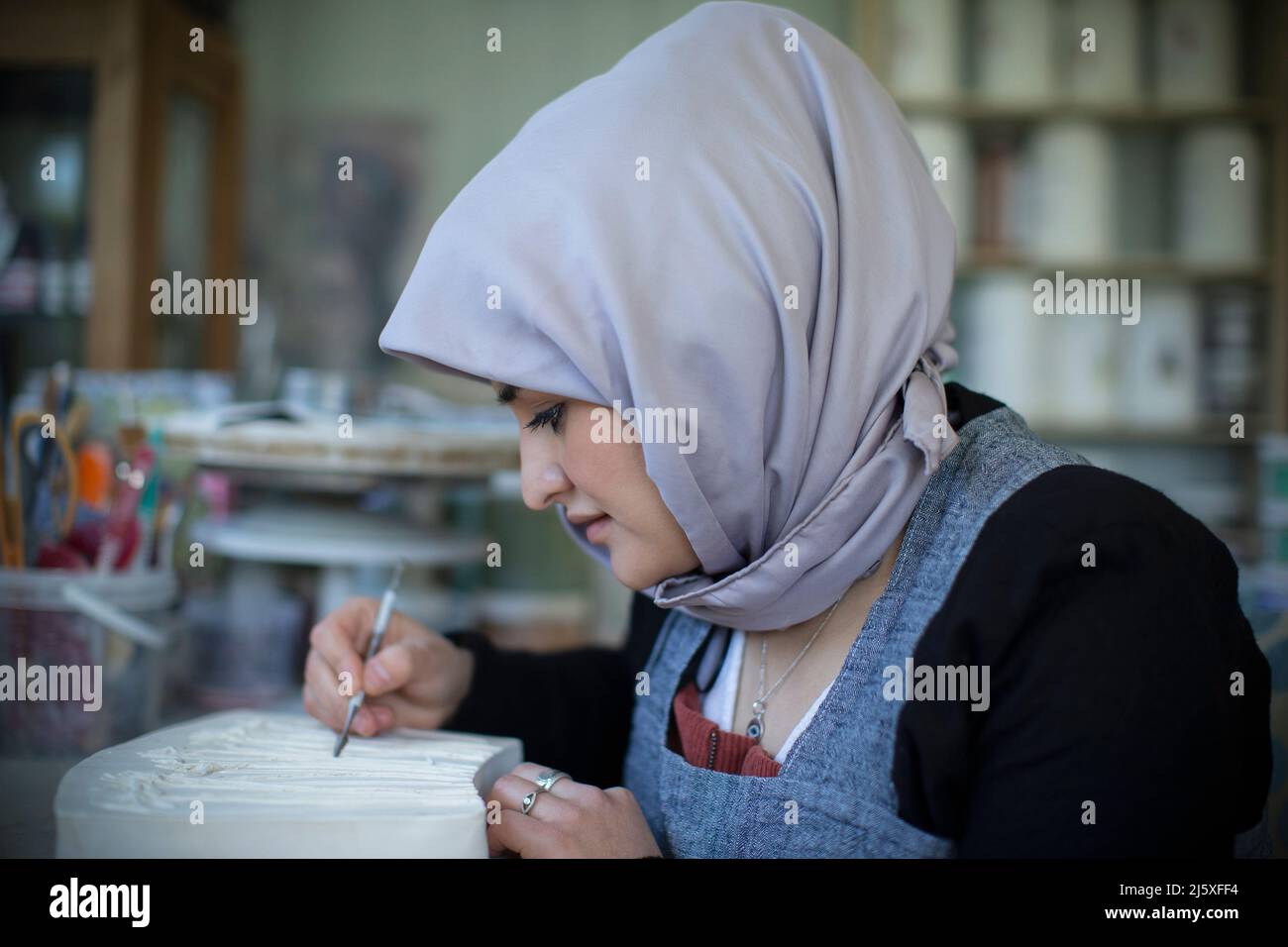 Young female Muslim artist working in art studio Stock Photo
