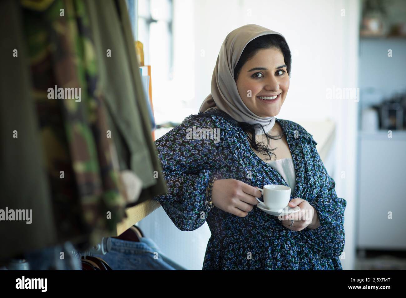 Portrait confident young Muslim woman in hijab drinking coffee Stock Photo