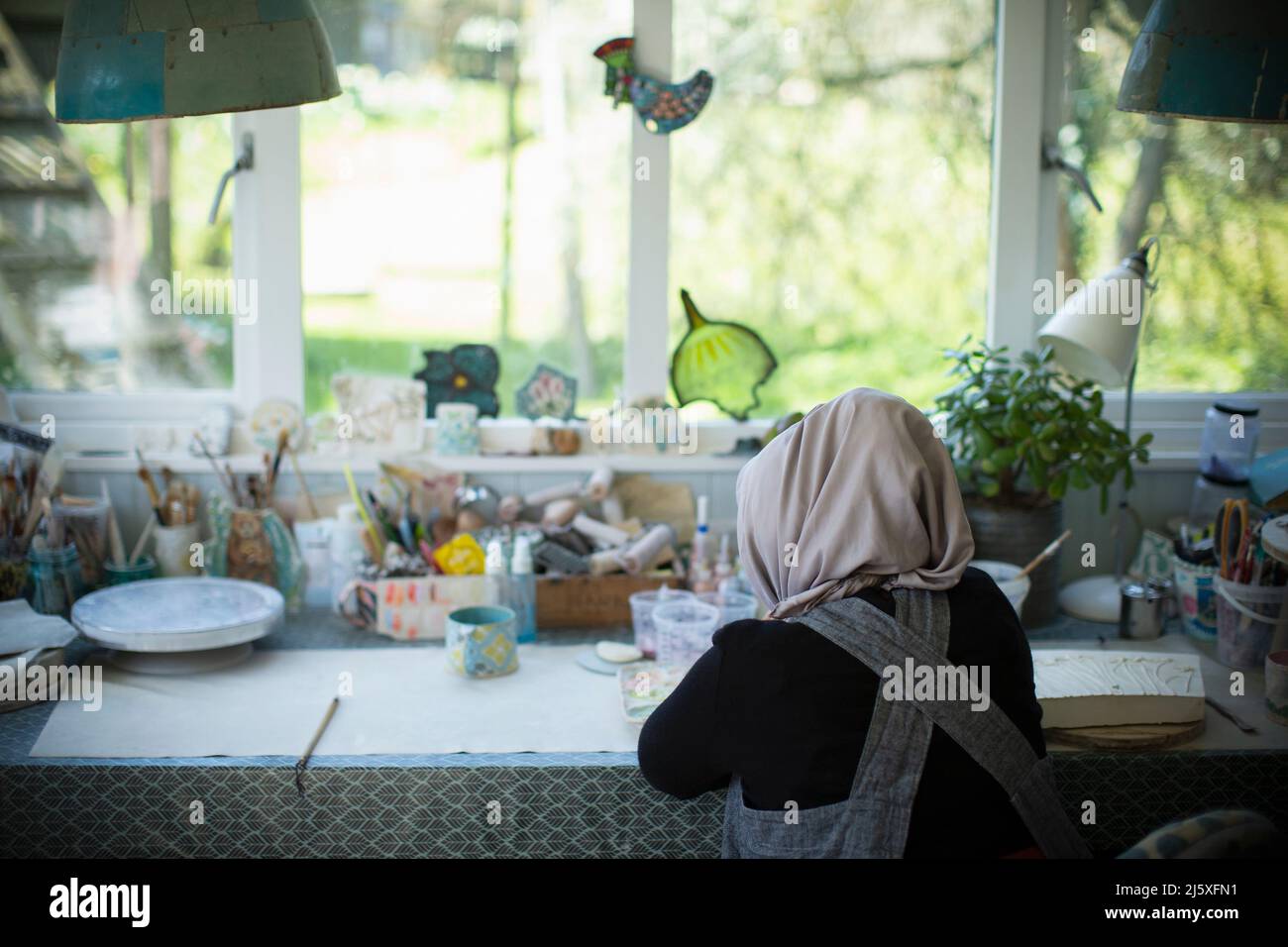 Young female artist in hijab working in art studio Stock Photo