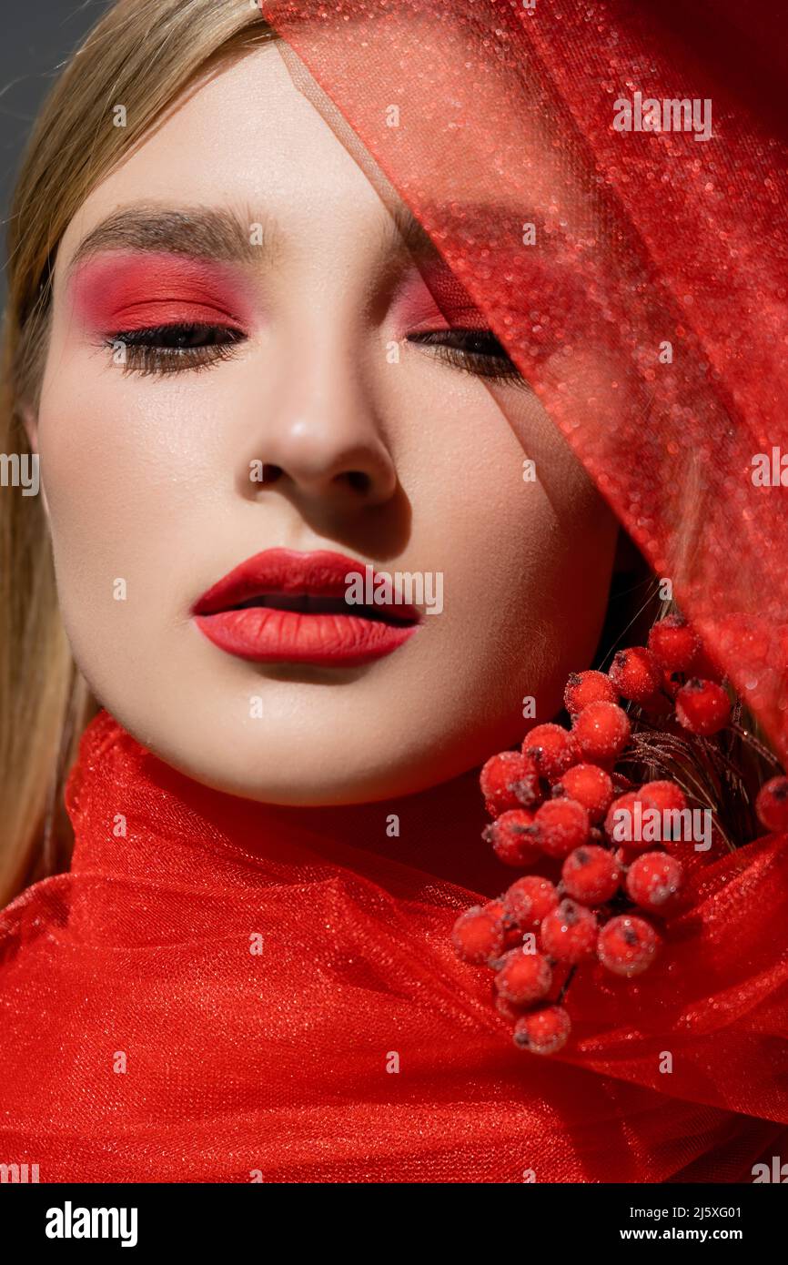Portrait of pretty model with red visage posing near cloth and berries isolated on grey Stock Photo