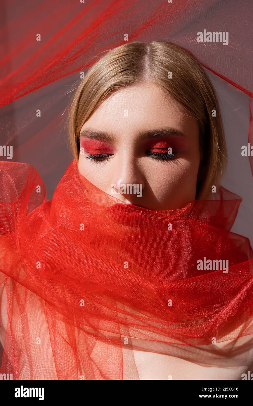 Young fair haired model in red cloth on grey background Stock Photo - Alamy