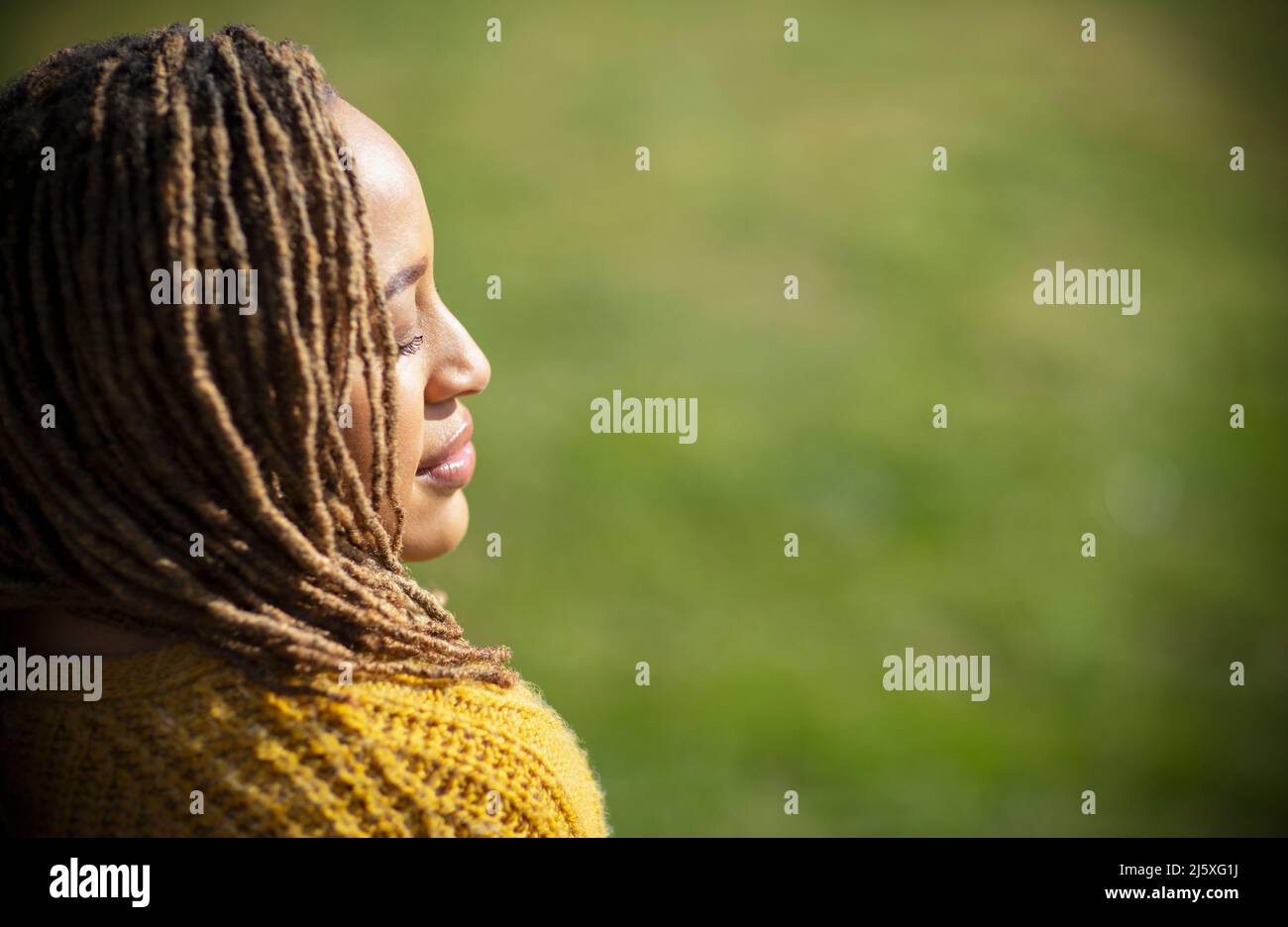 Serene young woman basking in sunlight with eyes closed Stock Photo
