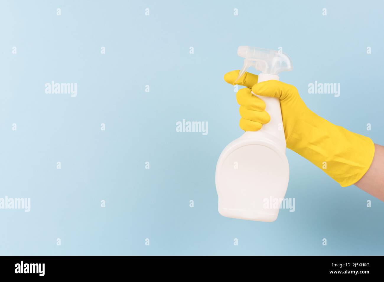 Hand in yellow protective rubber glove holding spray bottle with ...
