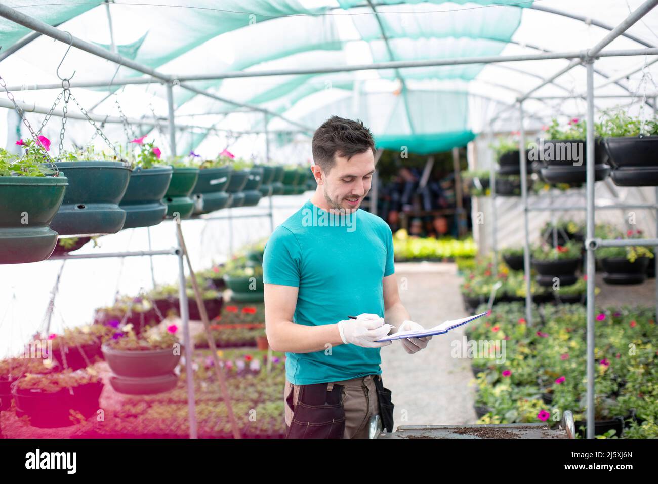 Male garden shop owner with clipboard in greenhouse Stock Photo