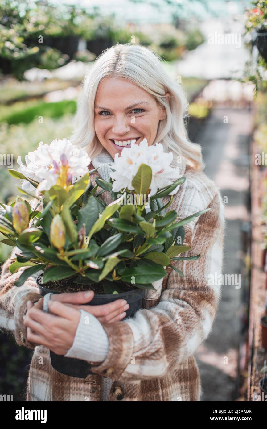 Portrait happy woman holding potted flower Stock Photo