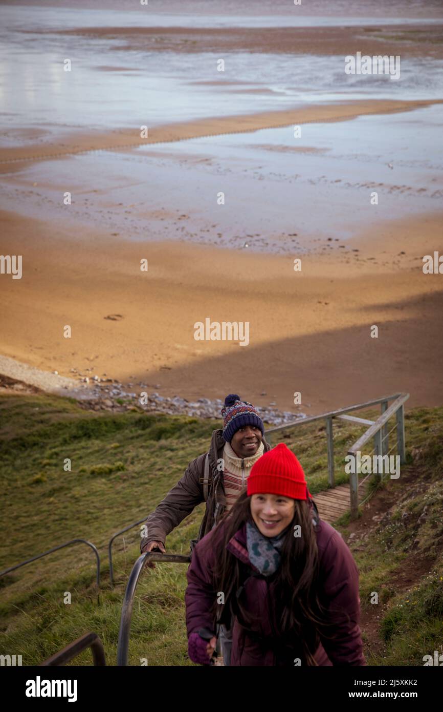 Happy couple hiking up steps over winter beach Stock Photo