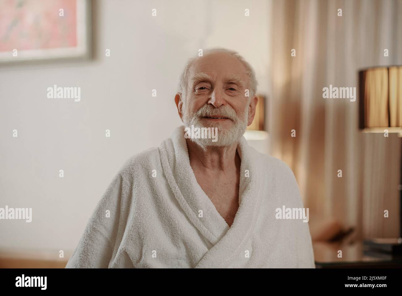 A gray-haired bearded man in a white robe in a hotel room Stock Photo ...