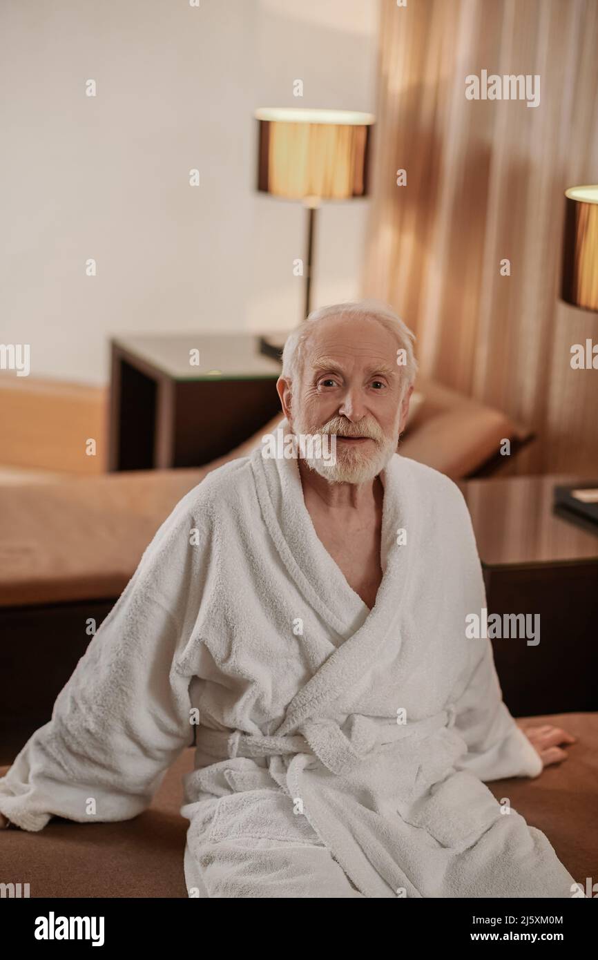 A gray-haired bearded man in a white robe in a hotel room Stock Photo ...