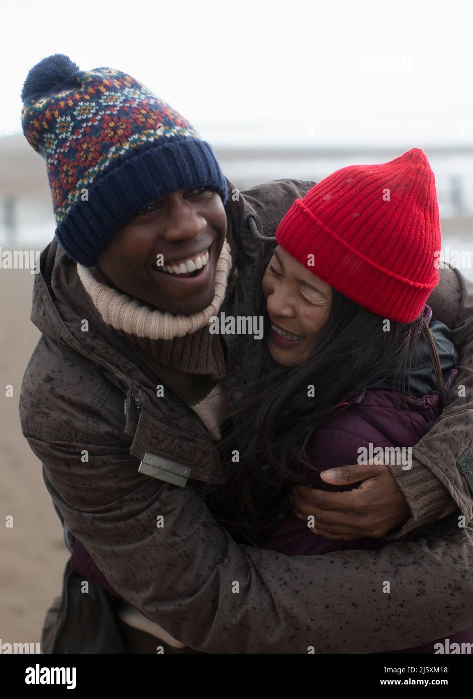 Happy carefree couple in warm clothing hugging Stock Photo